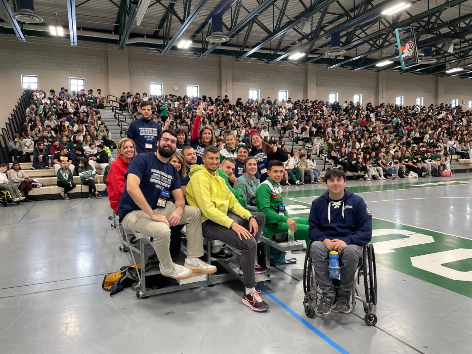 A delegation of sports administrators from Bulgaria waits on the court of a school gym during a unified sports event. 